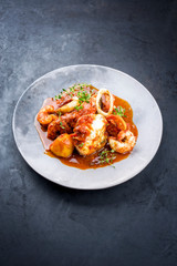 Traditional Brazilian fish stew moqueca capixaba with fish filet and king prawns in tomato sauce as...
