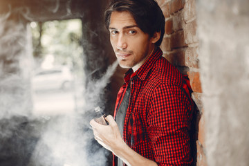 Stylish man in a city. Elegant male use the electronic cigarette