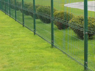 neat green fence and bushes of a park zone in the city