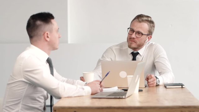 team of two male office clerk working together, smiling, talking and discussing statistics drom laptop. business man reading from screen. working on project idea, workspace. cooperation