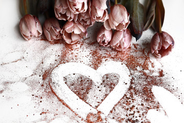 Bunch of dusty pink tulips laying on the table with bronze glitter heart. Wedding backdrop.