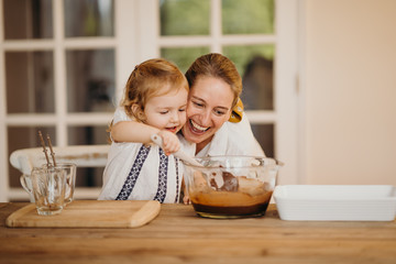 Loving beautiful mother and daughter cooking together a chocolate brownie and having fun