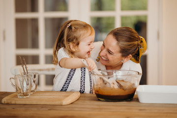 Loving beautiful mother and daughter cooking together a chocolate brownie and having fun