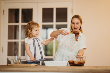 Loving beautiful mother and daughter cooking together a chocolate brownie and having fun