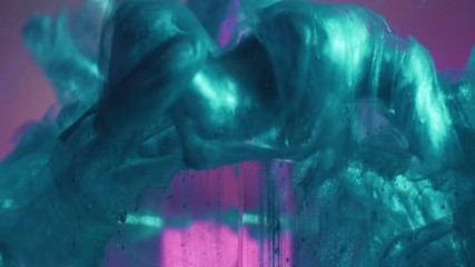 Ink splash. Surreal power. Aqua menthe green glitter liquid motion over pink glass cube in water.