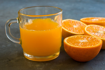 A glass with orange juice and some oranges around
