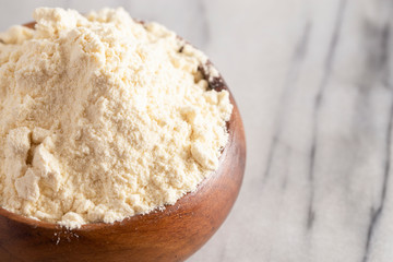 Bowl of Millet Flour in a Wood Bowl on a White Marble Countertop