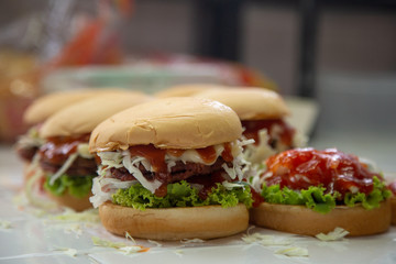 hamburger fast food  meal delicious American in the  restaurant, burger  Decorated with onion cherry tomatoes, Close-up of homemade tasty burgers on wooden table, Craft beef burgers with vegetables