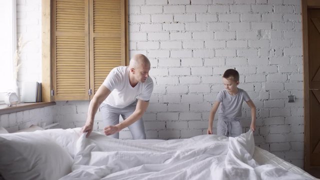 He was making the beds. Мальчик заправляет кровать.