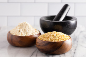 Whole Millet and Millet Flour in a Wood Bowl on a White Marble Countertop