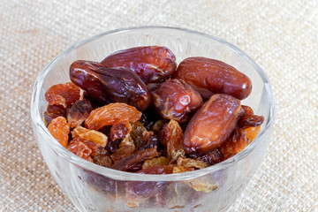 Dates and raisins in a transparent plate on burlap