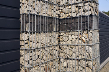 A fragment of the fence surrounding the property. Gabion wall.