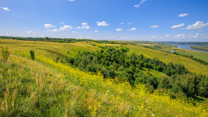 Fototapeta na wymiar hills overgrown with grass and trees on the banks of the Vyatka River