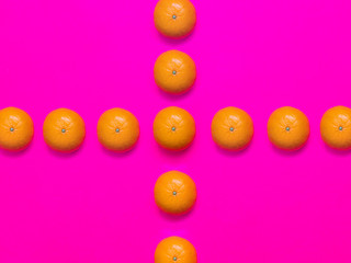 Colorful fruit pattern of fresh mandarins on a pink background. Top view