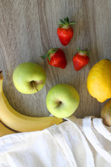 Canvas tote bag with bananas, apples, pear, lemon and strawberries. Top view.