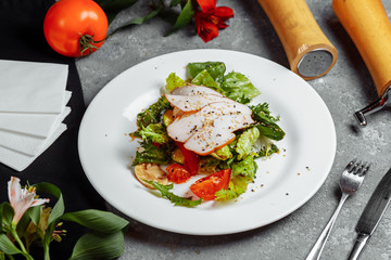 Salad with meat, tomato, lettuce sprinkles, crab. Chicken meat and tomatoes with cucumber on a gray background. Food and food concept