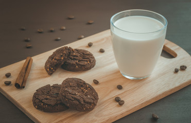 glass of milk and chocolate cookies on a wooden background