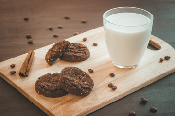 glass of milk and chocolate cookies on a wooden background