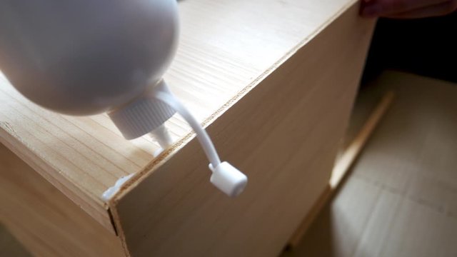 DIY concept, hand of young woman applies glue on wooden surface