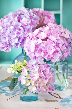 beautiful purple hydrangea flowers in a vase on a table .
