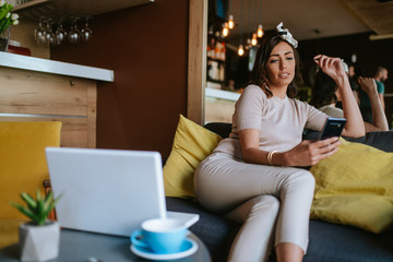 Obraz premium An attractive young caucasian woman with a phone in her hand sits in a cafe
