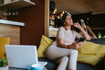 Obraz premium An attractive young caucasian woman with a phone in her hand sits in a cafe