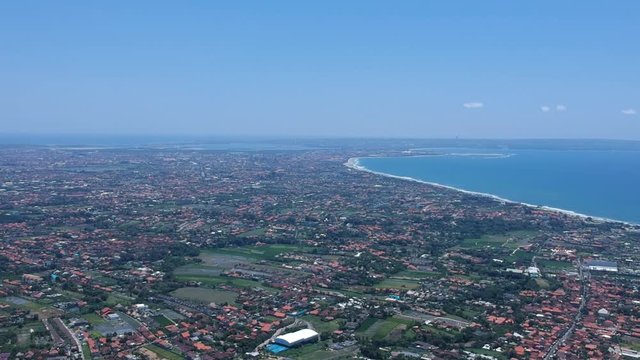 changu and kuta from a height in sunny weather bali indonesia, visible red roofs, bali airport green rice fields and the ocean in the background
