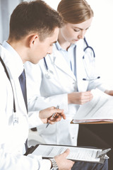 Doctors writing papers using clipboard. Physicians discussing medication program or studying at medical conference. Healthcare, insurance and medicine concept