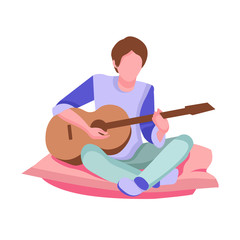 Young guy plays the guitar, musician, teenager free time, spends time on the pillow, sitting in the living room,
