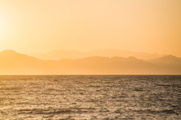 hazy, colorful, orange sunset over layers of mountains on the nile of egypt