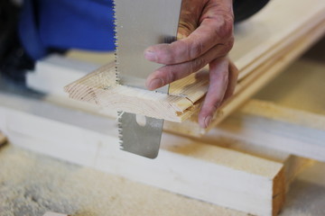 a saw cuts wooden boards, which is in the hand of a man, the concept of repair, construction, natural materials