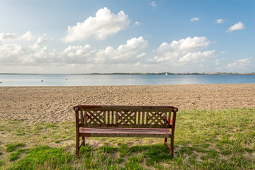 Fototapeta na wymiar Lonely bench facing beautiful beach at the Baltic Sea in Northern Germany