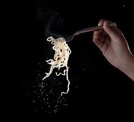 Hand holding fork to eat instant noodles with steam and smoke isolated on black background