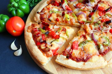 Food- Traditional Italian veggie pizza. Toppings are capsicum, corn, tomatoes, onion, red chilies and cheese. Ingredients and vegetables background with copy space.