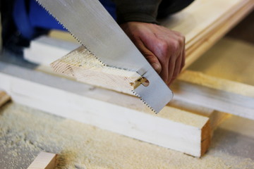 a saw cuts wooden boards, which is in the hand of a man, the concept of repair, construction, natural materials