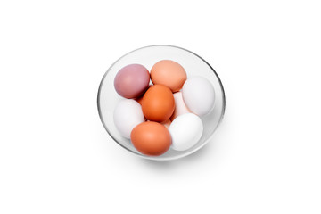 eggs of different colors from white to brown in a glass bowl, isolated on a white background