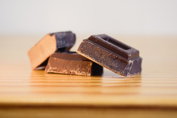 Onzas de chocolate negro sobre mesa de madera con fondo blanco desenfocado