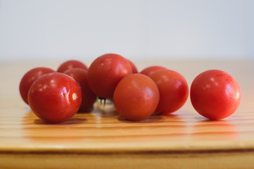Tomates cherry sobre una mesa de madera con fondo claro desenfocado