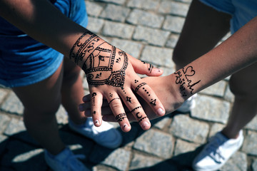 Tattooing with henna on the hands of two western girls.