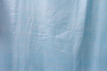 Light blue creased fabric close-up, top view background