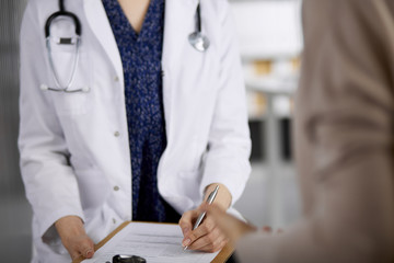 Doctor and patient discussing current health examination while sitting in clinic. Perfect medical...