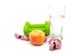 yellow Apple and green dumbbells, Measuring tape with a glass of water isolated on a white table