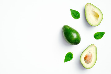 Ripe sliced avocado with green leaves on white background. Flat lay, top view, copy space