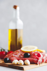 A close-up of pork steaks marinated in spices, with olives and lemon on them. Vertical orientation. Grilling meat