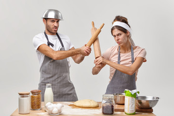 Photo of professional cooks have battle at kitchen, participate in culinary contest, fencing with rolling pins, prepare fresh dough for baking pie, make cookie dessert. Chef contest who is best