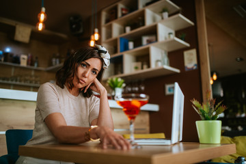 Attractive young caucasian woman drinking alcohol in a cafe