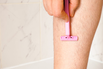 Woman shaving her leg in bathroom. Closeup