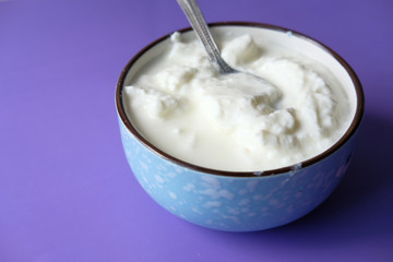 close up of fresh yogurt in a bowl on color background 
