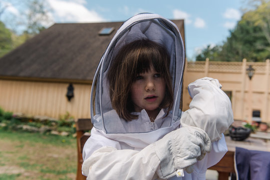 little girl getting dressed in apiarist suit to check on beehive