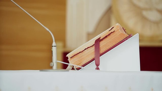 Old prayer book, priest book, Bible with red cover and bookmark lies on a white altar, pulpit